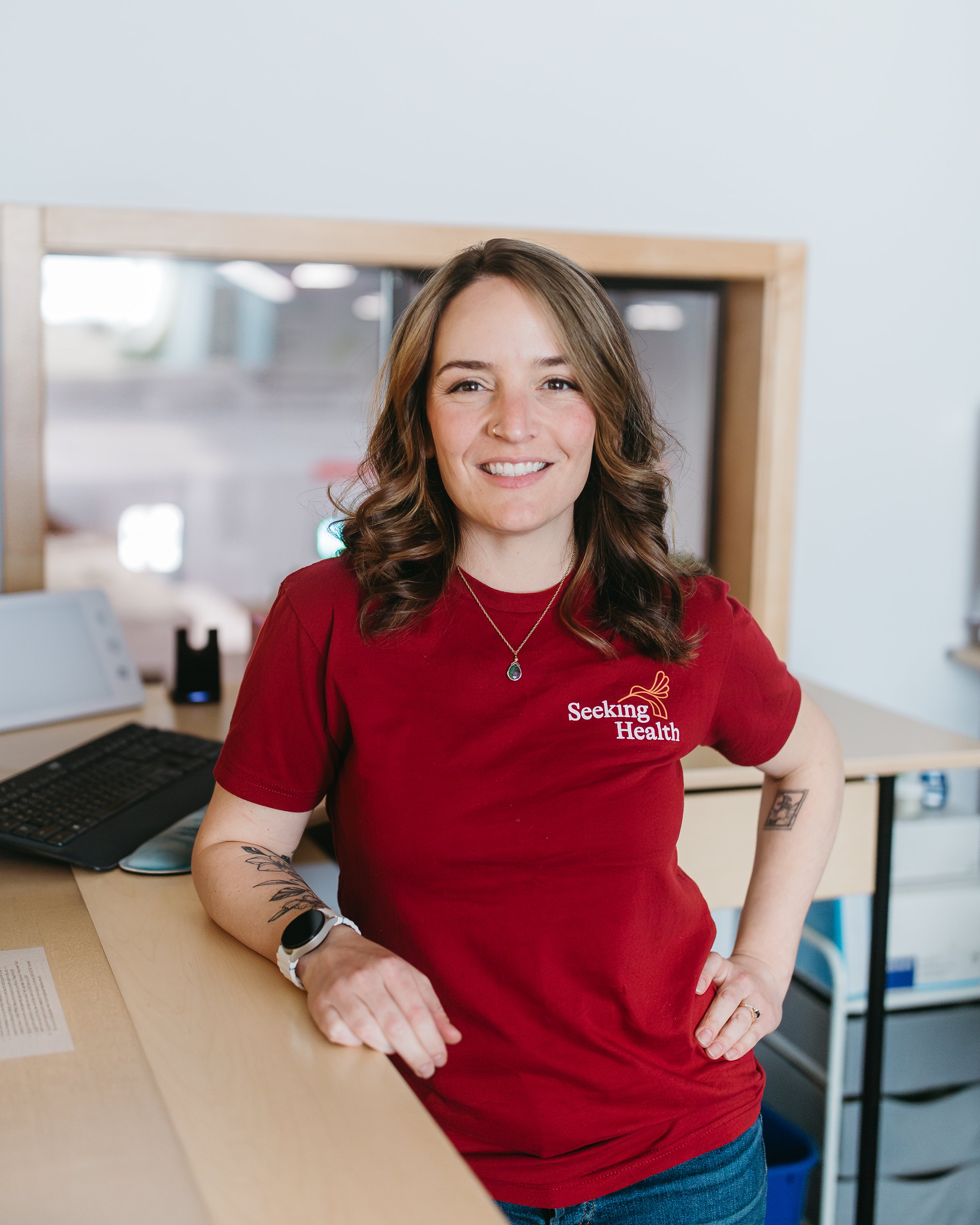 Person wearing a red 'Seeking Health' t-shirt in an office setting