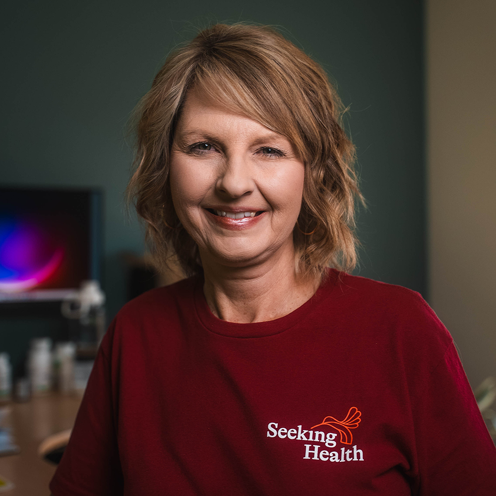 Woman wearing a red 'Seeking Health' shirt in an indoor setting
