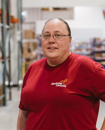 Person wearing a red 'Seeking Health' shirt in a warehouse setting