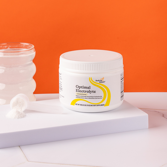 Jar of 'Optimal Electrolyte' supplement on a white surface with an orange background