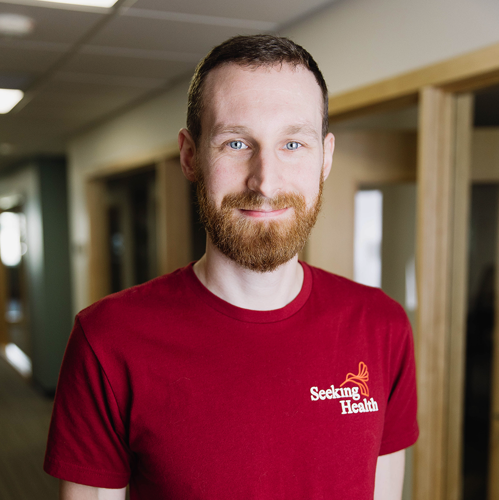 Man wearing a red 'Seeking Health' t-shirt in an indoor setting