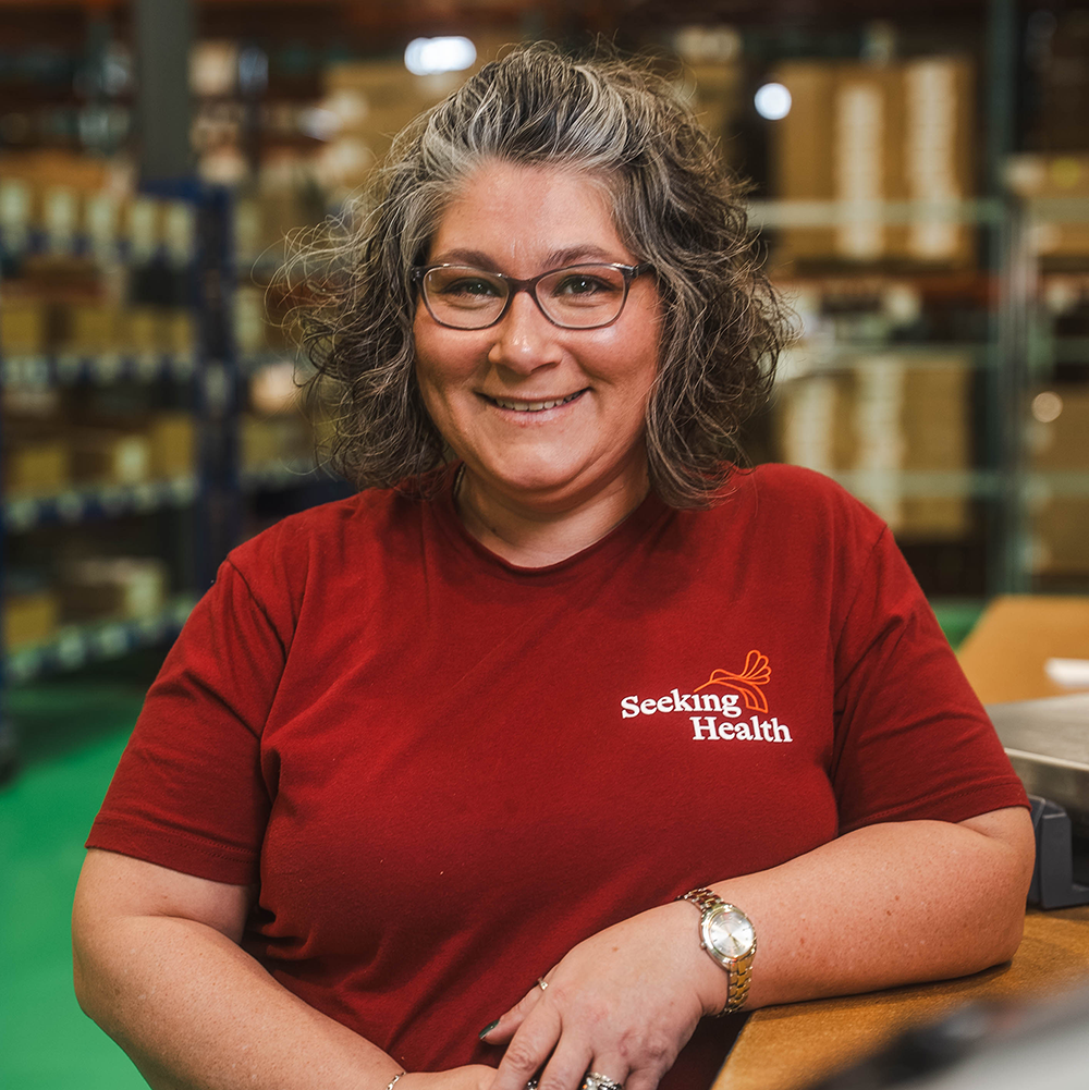 Person wearing a red 'Seeking Health' shirt in a warehouse setting