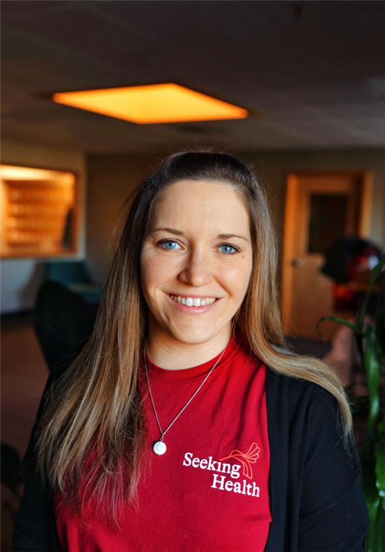Woman wearing a red 'Seeking Health' shirt in an indoor setting