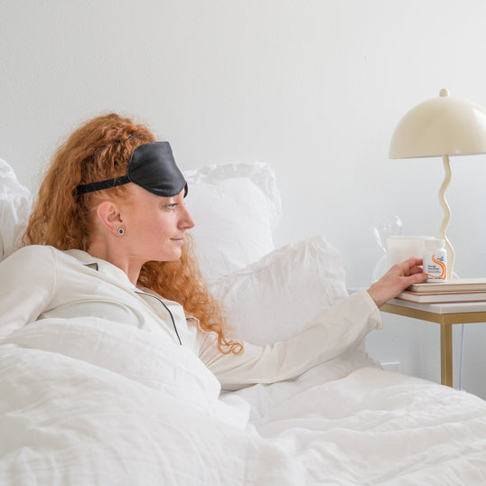 Image of woman in bed reaching for product