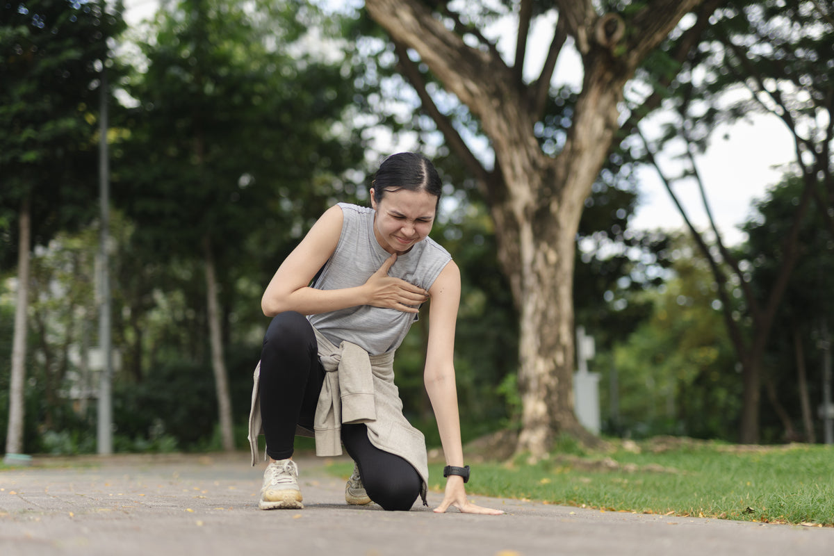 Woman experiencing chest pain outdoors in a park