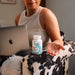 Person sitting on a couch with a laptop and a bottle of supplements | AB-1