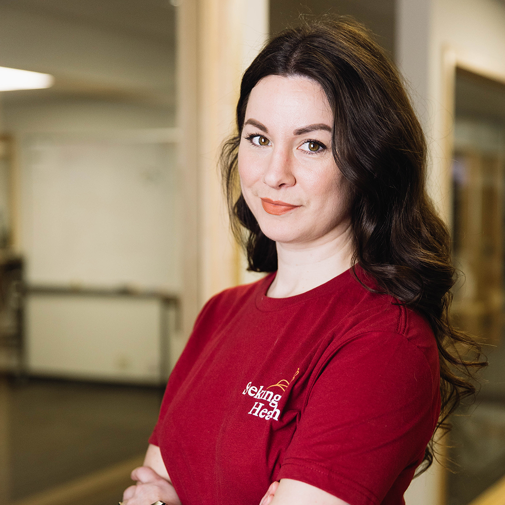 Woman wearing a red shirt with a logo in an indoor setting