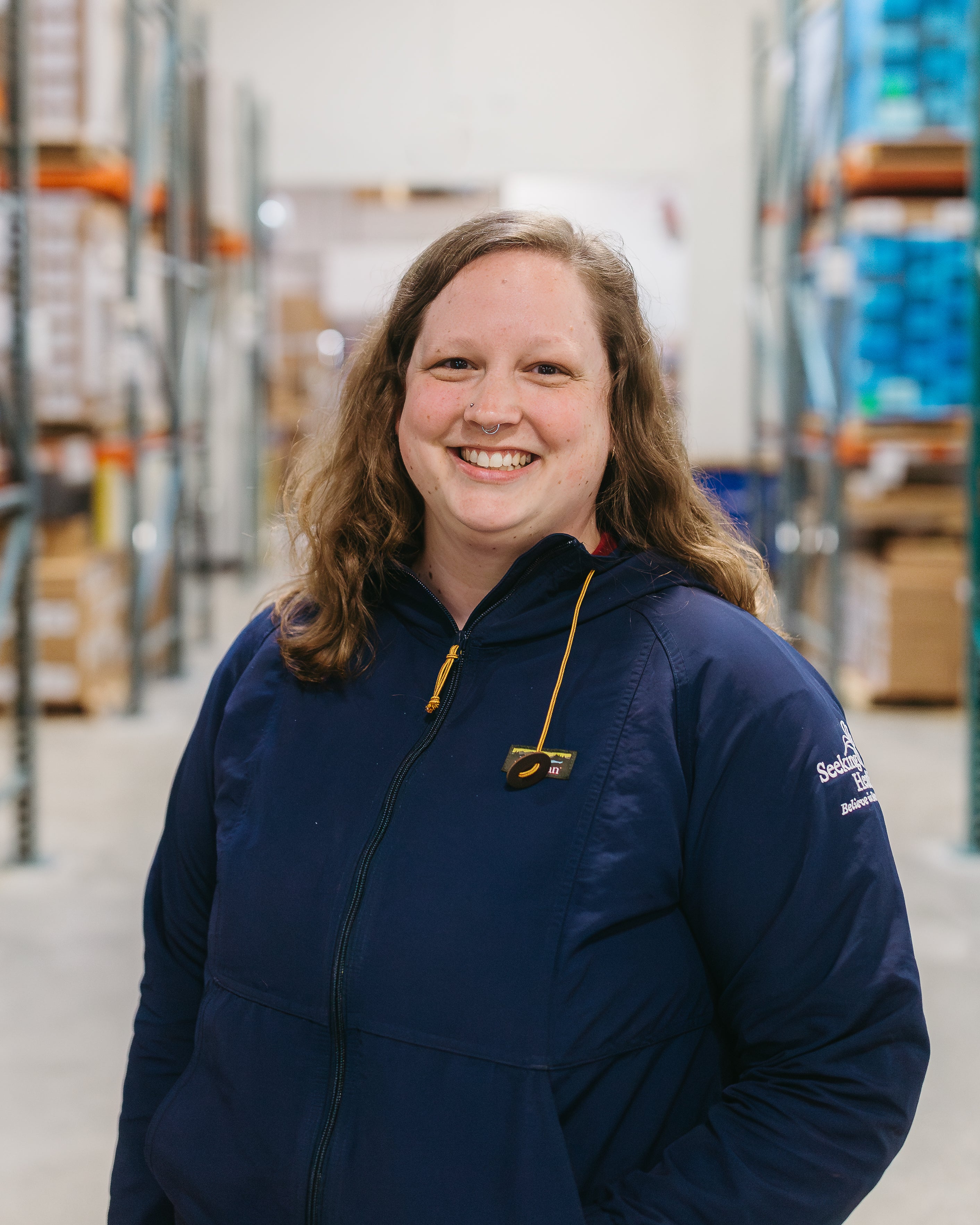 Person wearing a blue jacket in a warehouse setting