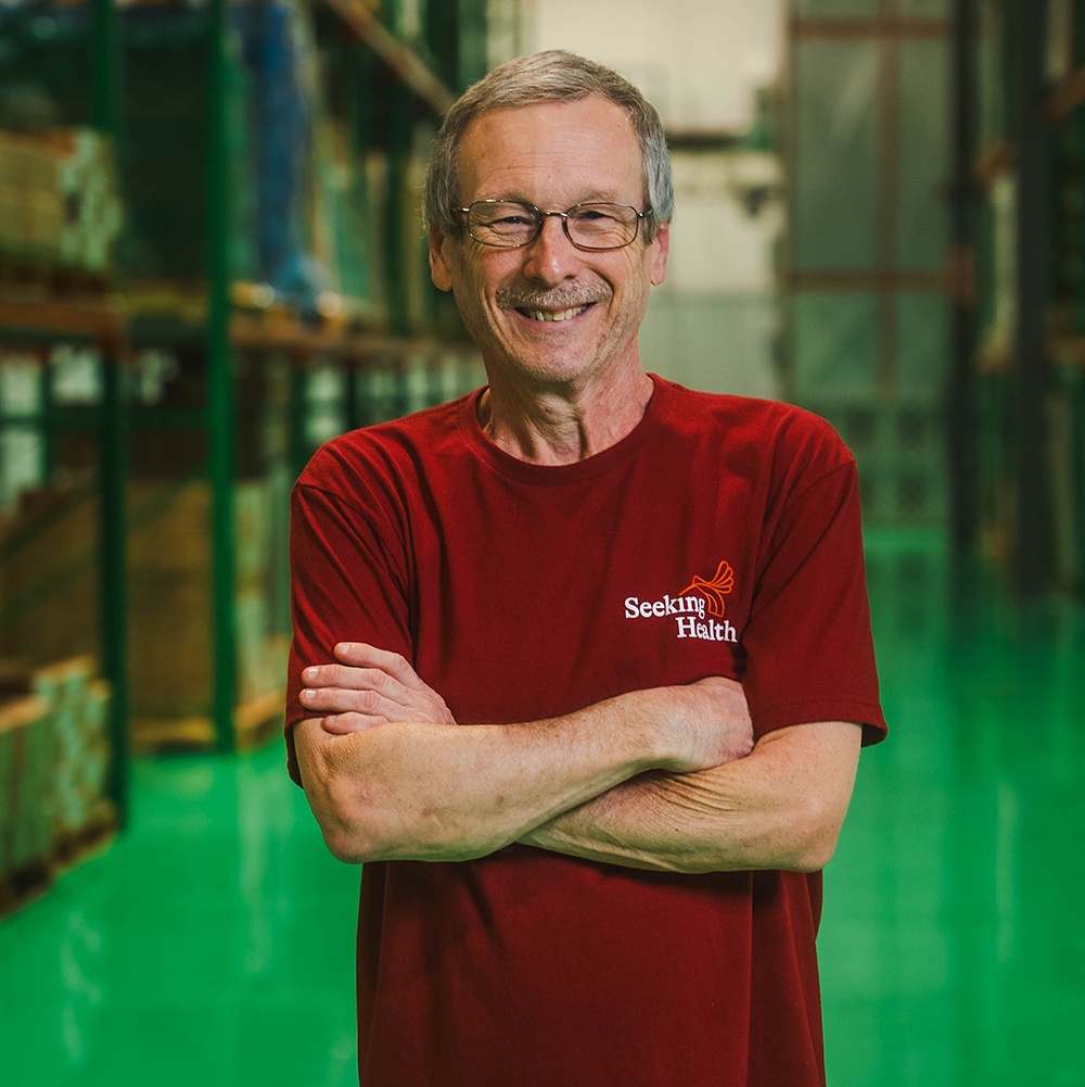 Man wearing a red 'Seeking Health' shirt in a warehouse setting