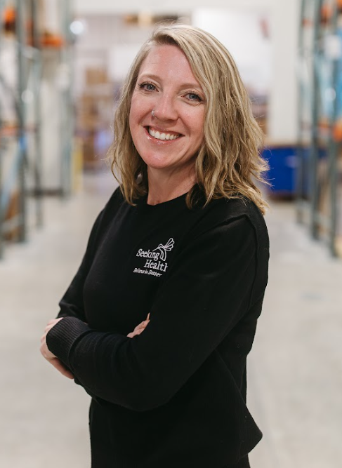 Woman wearing a black sweatshirt with a logo in a warehouse setting