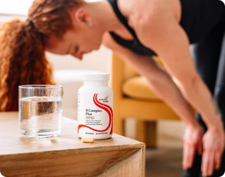 Person stretching with a bottle of supplements and glass of water on a table