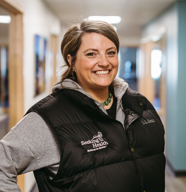Person wearing a black vest with 'Seeking Health' logo in a hallway